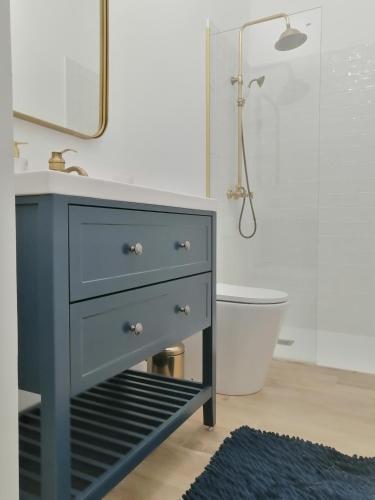 La salle de bains est pourvue d'une commode bleue et d'un lavabo. dans l'établissement Chez Joséphine, à Gerville