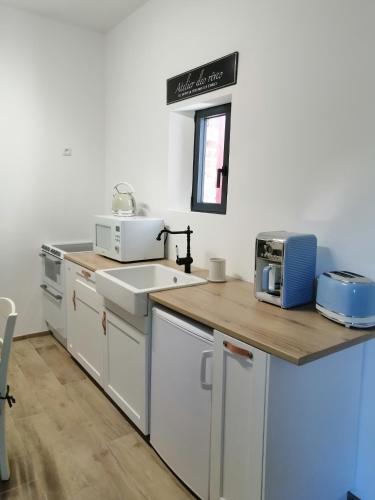 une cuisine avec un comptoir avec un évier et un micro-ondes dans l'établissement Chez Joséphine, à Gerville