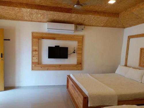 een slaapkamer met een bed en een tv aan de muur bij Royal Cottage, Anaimalai room in Pollāchi