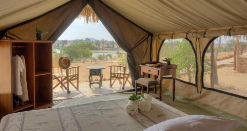 namiot z łóżkiem, stołem i krzesłami w obiekcie Kudu Safari Camp w mieście Koito