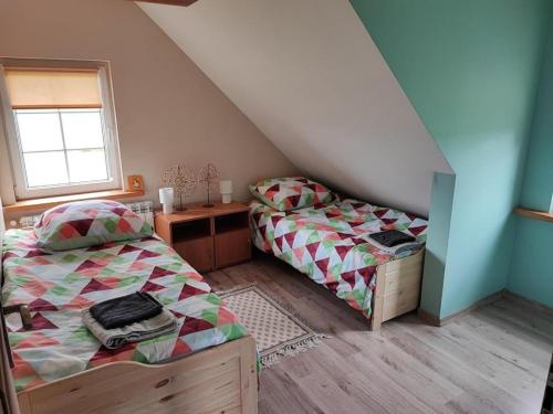 sypialnia z 2 łóżkami, biurkiem i oknem w obiekcie Domek nad stawem 