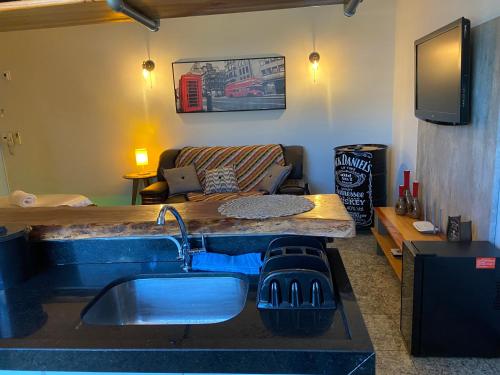 a kitchen with a sink and a table and a couch at Apart Hotel Seg Total Lofts Encantadores in Mogi-Guaçu