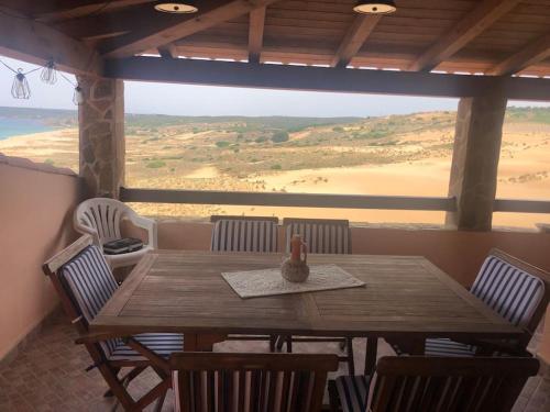 uma mesa e cadeiras de madeira com vista para o deserto em La Villa dell Artista con vista mare e dune - IUN Q7440 em Torre dei Corsari
