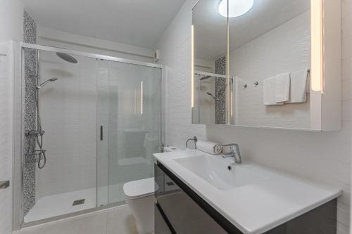a white bathroom with a sink and a shower at LosCristianos Front Line of Ocean WiFi in Los Cristianos