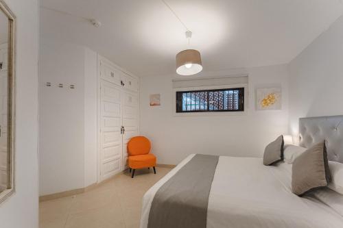 a bedroom with a bed and a orange chair at LosCristianos Front Line of Ocean WiFi in Los Cristianos