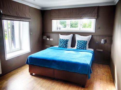 ガディンヌにあるB&B Aux 4 Saisonsのベッドルーム1室(青いベッド1台、窓2つ付)