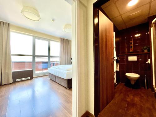 a bedroom with a bed and a bathroom with a window at Balu Apartments in Prague