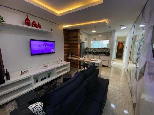 a living room with a couch and a tv on a wall at Apart Hotel Seg Total Lofts Encantadores in Mogi-Guaçu