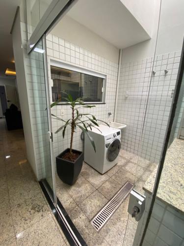 a bathroom with a washing machine and a plant at Apart Hotel Seg Total Lofts Encantadores in Mogi-Guaçu