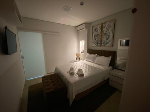 a bedroom with a bed with a pair of shoes on it at Apart Hotel Seg Total Lofts Encantadores in Mogi-Guaçu