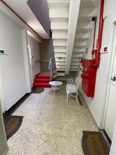 a hallway with two chairs and a table and stairs at Apart Hotel Seg Total Lofts Encantadores in Mogi-Guaçu
