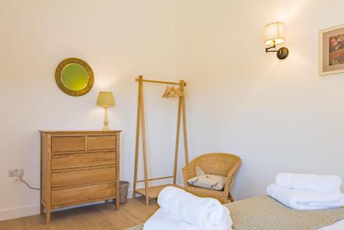 a bedroom with two beds and a dresser and a mirror at The Parlour by Bloom Stays in Stalisfield