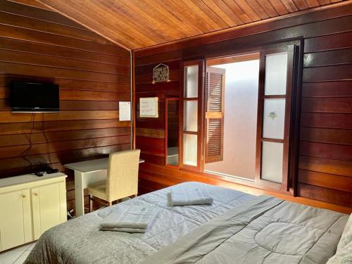 Schlafzimmer mit einem Bett, einem Schreibtisch und einem Fenster in der Unterkunft Família Capetti in Bauru