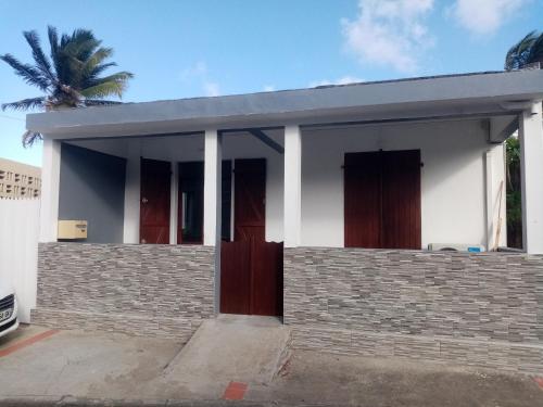 a small white house with a palm tree at Maison de vacances baca vue sur mer in Capesterre-de-Marie-Galante