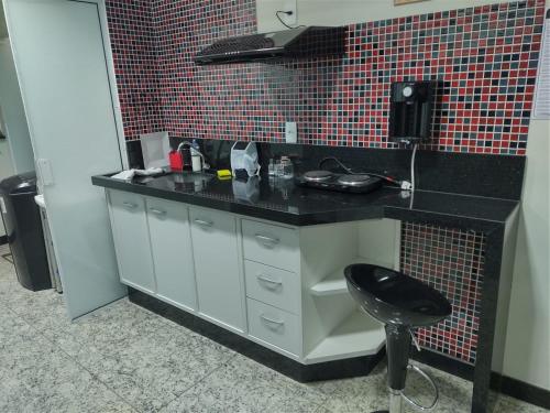 a kitchen with a black counter and a stool at Apart Hotel Seg Total Lofts Encantadores in Mogi-Guaçu