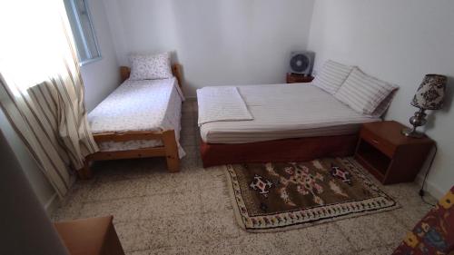 niewielka sypialnia z 2 łóżkami i dywanem w obiekcie Charmant logement avec jardin en permaculture w mieście Chebba