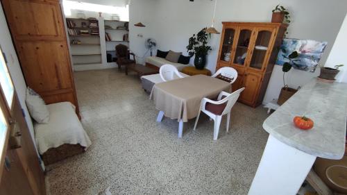 ein Wohnzimmer mit einem Tisch und weißen Stühlen in der Unterkunft Charmant logement avec jardin en permaculture in Chebba