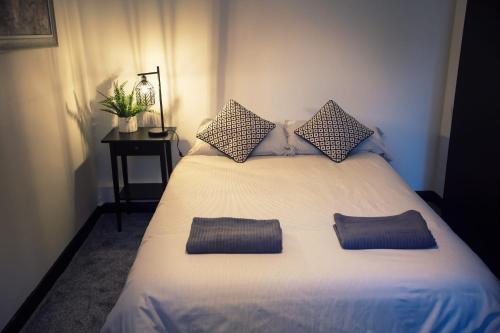 1 dormitorio con 1 cama blanca y 2 almohadas en The Basement, en Exeter