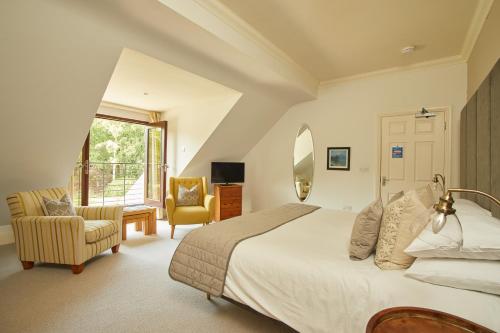 a bedroom with a bed and a chair and a window at Willowbeck Lodge Boutique Hotel in Carlisle