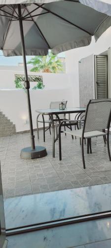 eine Terrasse mit einem Tisch, Stühlen und einem Sonnenschirm in der Unterkunft Anemone traditional house in Lardos