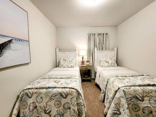 a bedroom with two beds and a table with a lamp at ENTIRE HOME- Gorgeous 3br Townhome Pool, Grill, Washer, Dryer, 2 FREE drive up spaces Sleeps 6 Close to everything PCB! in Panama City Beach