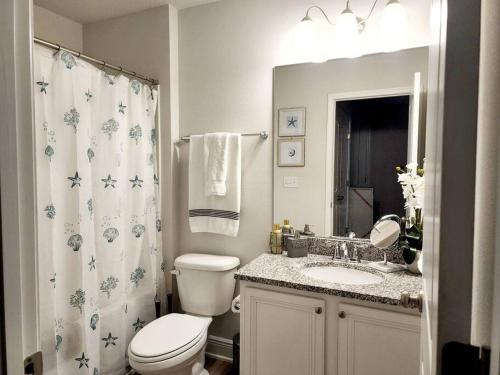 a bathroom with a toilet and a sink and a shower curtain at ENTIRE HOME- Gorgeous 3br Townhome Pool, Grill, Washer, Dryer, 2 FREE drive up spaces Sleeps 6 Close to everything PCB! in Panama City Beach