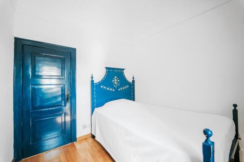 a bedroom with a blue door and a white bed at O Conventinho in Évora