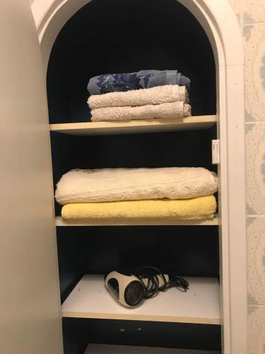 un placard avec des serviettes et une souris d'ordinateur sur une étagère dans l'établissement La Maison rose, à Fontiès-d'Aude