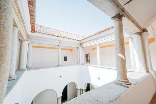 an empty room with white walls and columns at O Conventinho in Évora