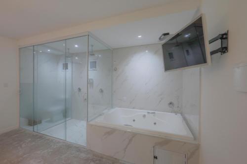 a bathroom with a tub and a glass shower at Sollaris Ecopousada in Japaratinga