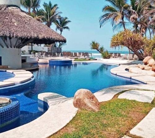 a swimming pool at a resort with palm trees and the ocean at Nuevo 3R 3B 1E Club Playa Gratis Tenis Padel Diamante Albercas in Acapulco