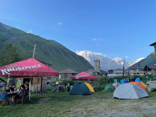 a group of tents in a field with mountains at Chvibiani Guesthouse & Bar in Ushguli