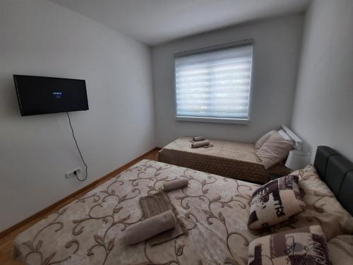 um pequeno quarto com uma cama e uma televisão de ecrã plano em Apartman TEJA DELUXE em Vrnjačka Banja