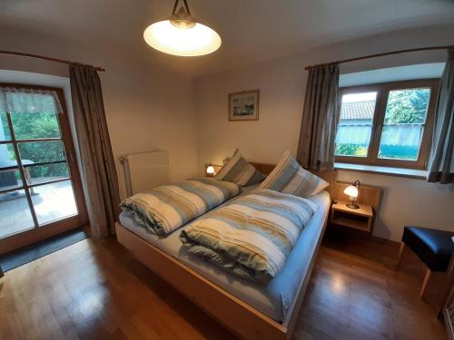 1 cama grande en un dormitorio con 2 ventanas en Haus Polleichtner, en Marquartstein