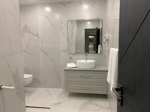 a white bathroom with a sink and a mirror at Hotel Ashot Erkat in Sevan