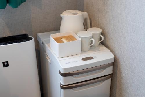 een witte koelkast met kopjes erop bij IMANO OSAKA SHINSAIBASHI HOSTEL - Vacation STAY 03958v in Osaka