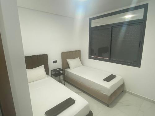 Cette petite chambre comprend 2 lits et un miroir. dans l'établissement Iquama Atawhid, à Nador