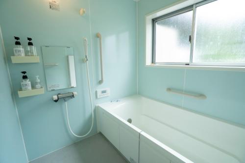 uma casa de banho branca com uma banheira e uma janela em I,K,I HOUSE SAIDOFURE - Vacation STAY 14778v em Iki