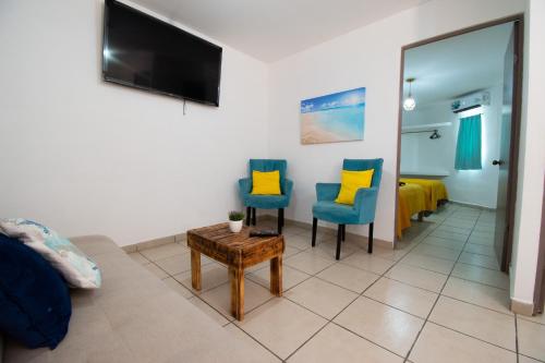 a living room with two blue chairs and a flat screen tv at Isla Venados Renta Vacacional in Mazatlán