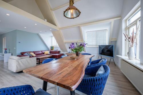 a living room with a wooden table and blue chairs at Hotel-Restaurant Loodsmans Welvaren in Den Hoorn