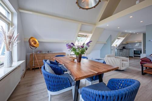 a dining room with a wooden table and blue chairs at Hotel-Restaurant Loodsmans Welvaren in Den Hoorn