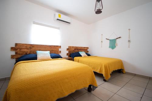 two beds in a room with yellow blankets at Isla Venados Renta Vacacional in Mazatlán