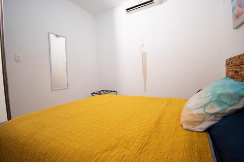 a bedroom with a yellow bed in a white room at Isla Venados Renta Vacacional in Mazatlán