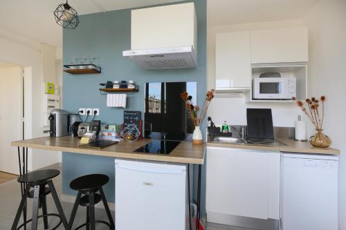 una cocina con armarios blancos y una barra con taburetes en expat renting - Le Bohème Nature - Proche Airbus, en Colomiers