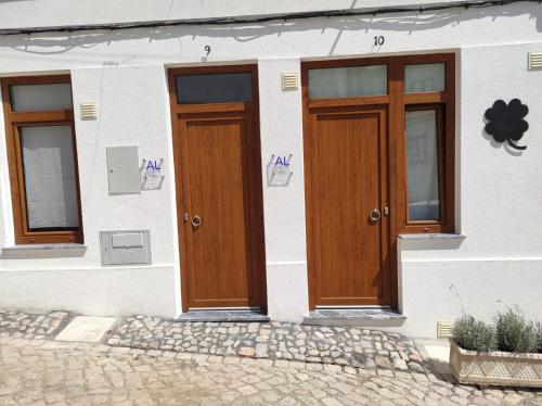 a white building with wooden doors on it at 7 Trevos Houses A in Santiago do Cacém
