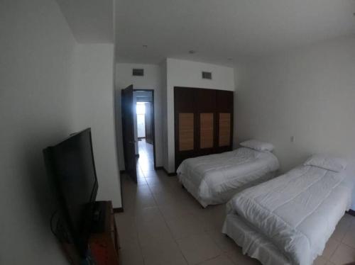 a bedroom with two beds and a flat screen tv at Jaco Carara Nativa Garden Suite ELEGANTE&EXCLISIVO in Puntarenas