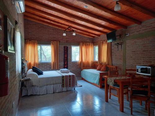 a bedroom with two beds and a table and a dining room at Mainame Traslasierra in Los Hornillos