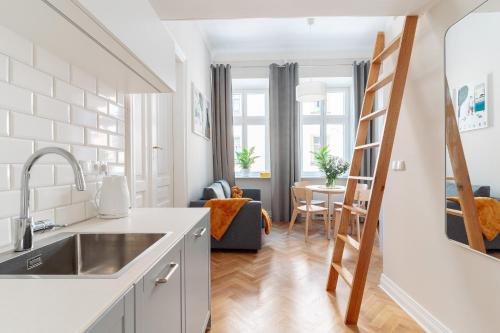 Kochanowskiego Family Apartments في كراكوف: مطبخ وغرفة معيشة مع سلم يؤدي إلى غرفة طعام