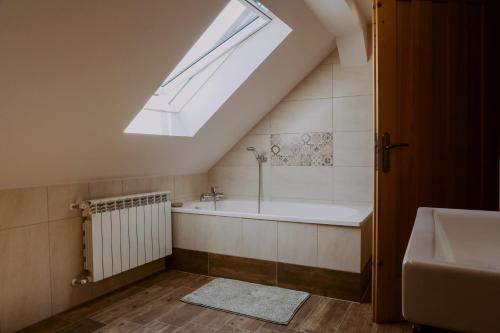 a attic bathroom with a bath tub and a skylight at Dom Wypoczynkowy - Alexander in Cisiec