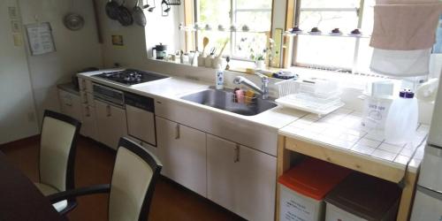 uma cozinha com um lavatório e um balcão com cadeiras em Minami Aso Guest House Hana hana - Vacation STAY 13316 em Takamori